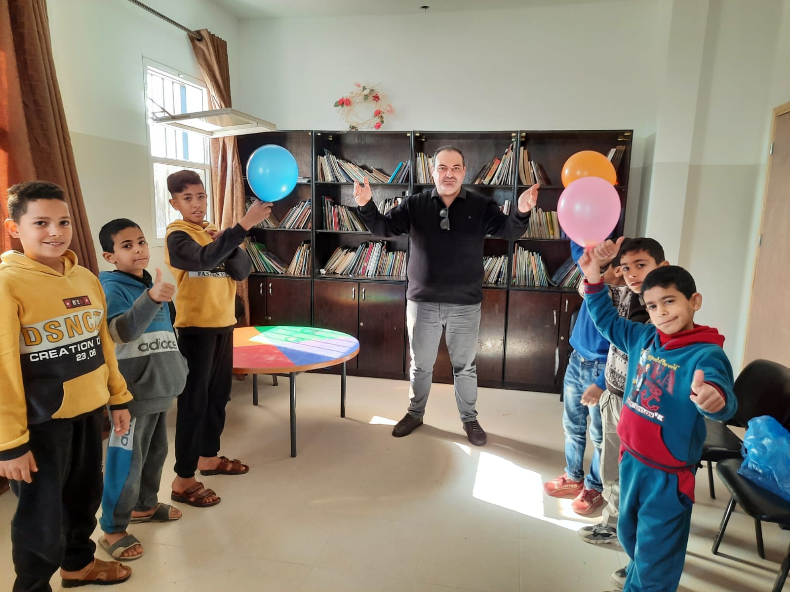 photo showing a group session with children holding balloons and an adult facilitator