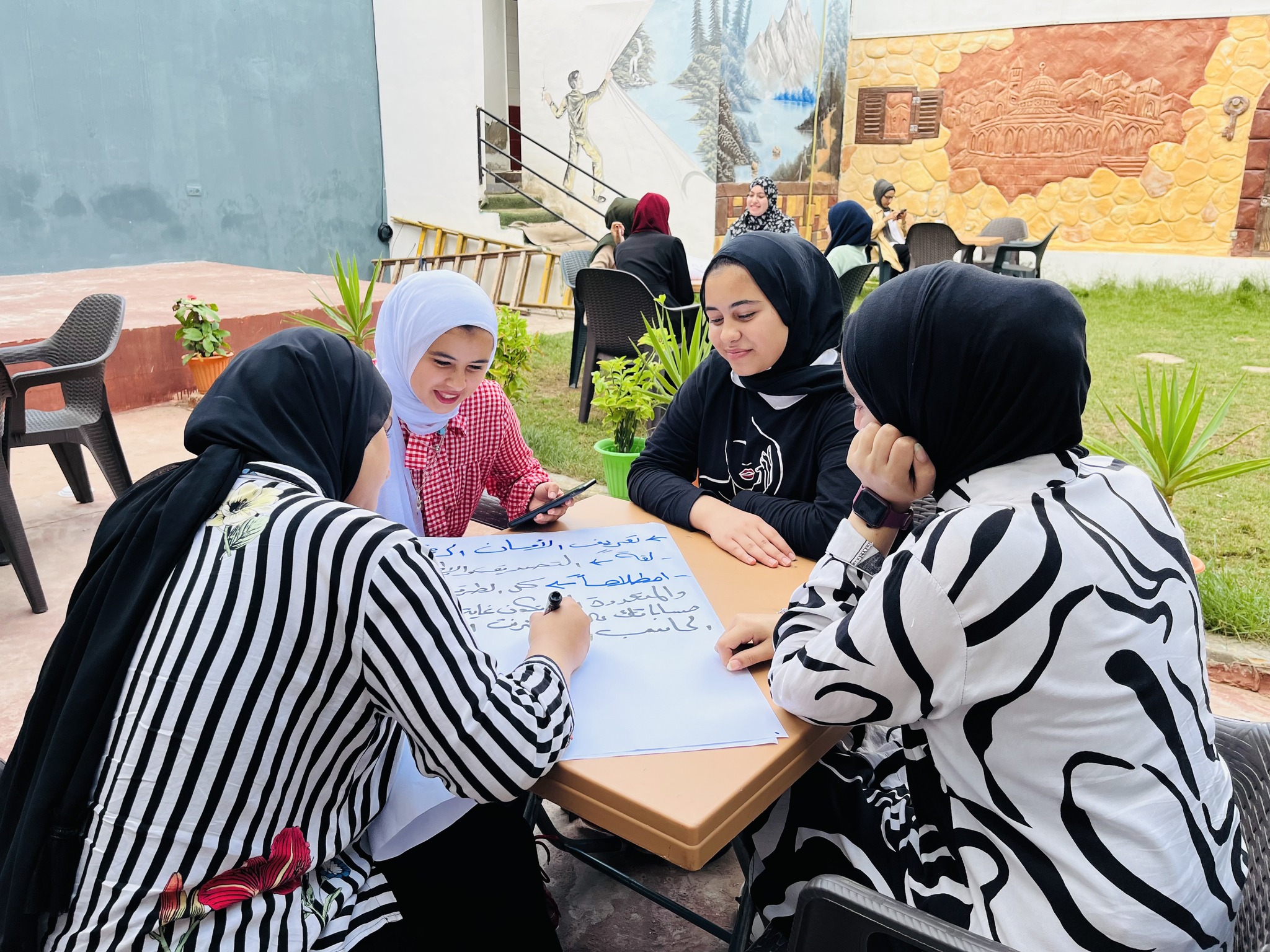 photo of 4 girls around a table writing on a flipchart